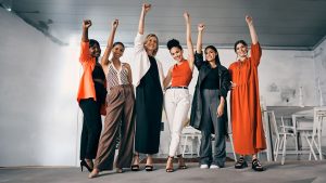 Eine Gruppe von Frauen mit verschiedenen Nationalitäten heben die Hände als Zeichen von Erfolg