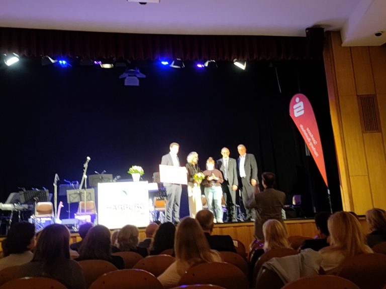 Mehrere Personen stehen auf einer Bühne und erhalten den Harburger Bürger:innen Preis für das Projekt Kiezläufer:innen