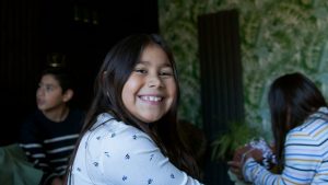 Lächelndes Mädchen mit anderen Kindern im Hintergrund – Einblick in aktuelle Projekte von IN VIA Hamburg.