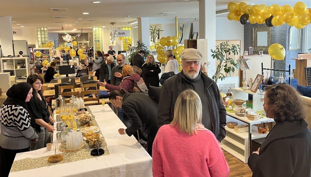 Empfang beim Jubiläum des Second-Hand Kaufhauses fairedelt. Die Menschen unterhalten sich in einem festlich dekorierten Laden.