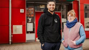 Rohan und Karla stehen vor einem roten Haus